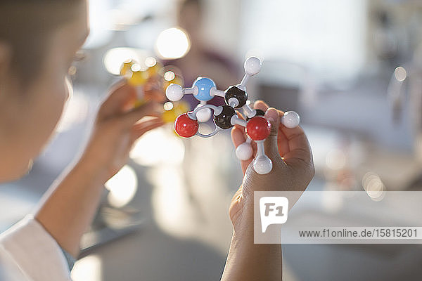 Neugierige Schülerin hält Molekülmodell im Klassenzimmer