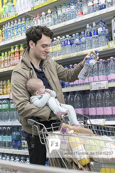 Father with baby daughter grocery shopping in supermarket