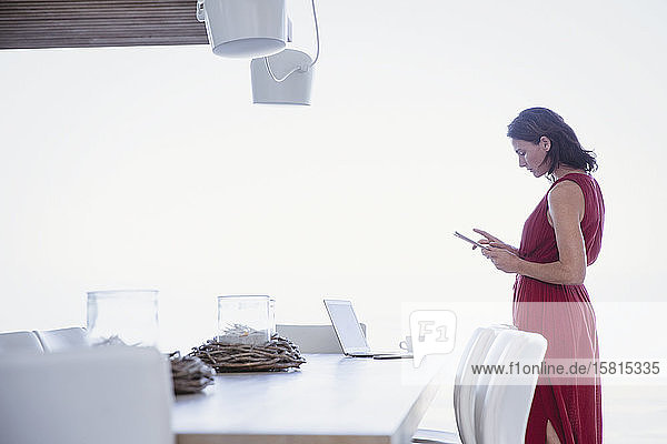 Frau mit digitalem Tablet  arbeitet am Esstisch