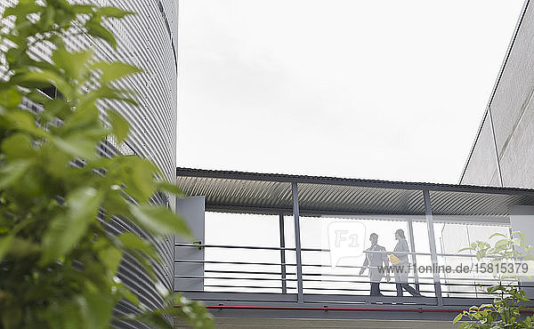 Supervisors walking on elevated walkway between factory buildings