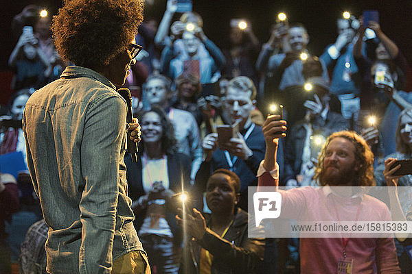 Audience using smart phone flashlights  watching speaker