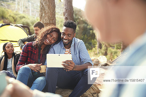 Lächelndes junges Paar benutzt digitales Tablet auf dem Campingplatz