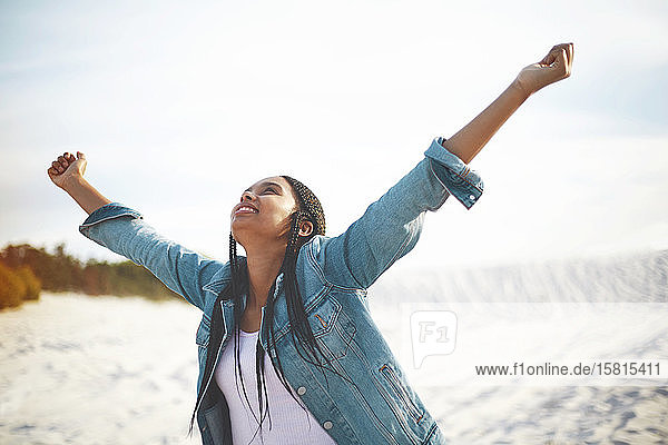 Exuberant young woman with arms outstretched on beach