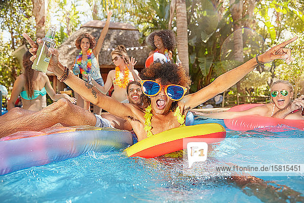 Portrait exuberant young friends drinking and playing in summer swimming pool