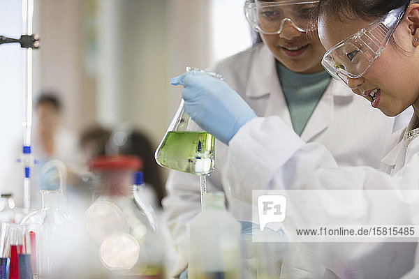 Studentinnen führen ein wissenschaftliches Experiment durch und untersuchen eine Flüssigkeit in einem Becherglas in einem Laboratorium