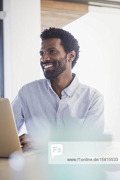 Smiling businessman working at laptop