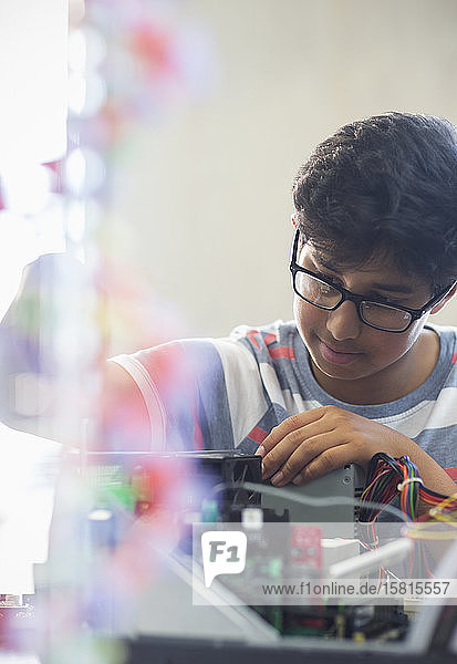Fokussierter Junge  der einen Computer im Klassenzimmer zusammenbaut