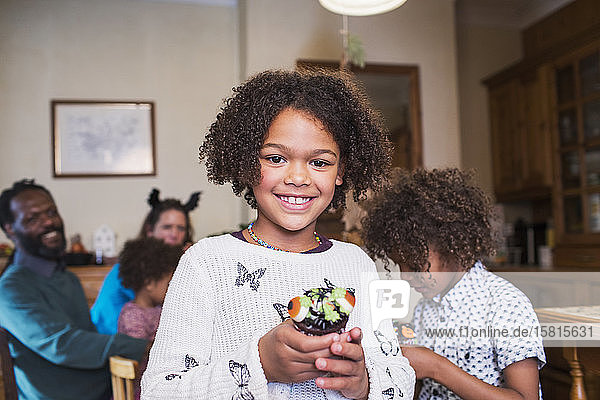 Porträt selbstbewusstes Mädchen hält dekorierten Halloween-Cupcake