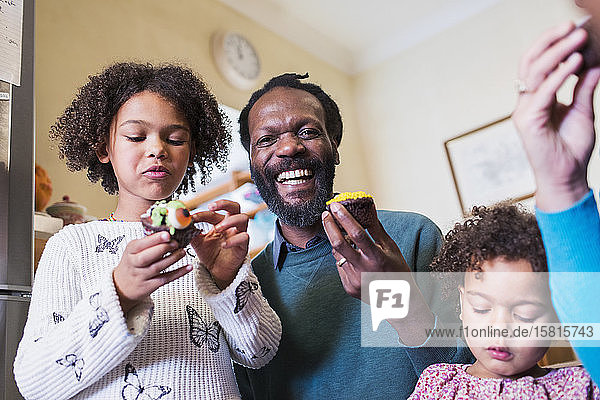 Porträt glücklicher Vater und Töchter  die Muffins essen