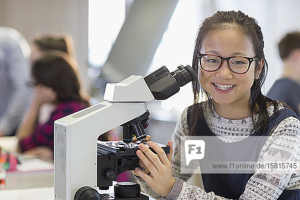 Porträt einer lächelnden  selbstbewussten Studentin  die ein Mikroskop benutzt und ein wissenschaftliches Experiment in einem Laboratorium durchführt