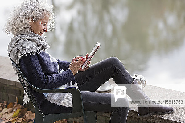 Aktive Seniorin mit digitalem Tablet am Parkteich