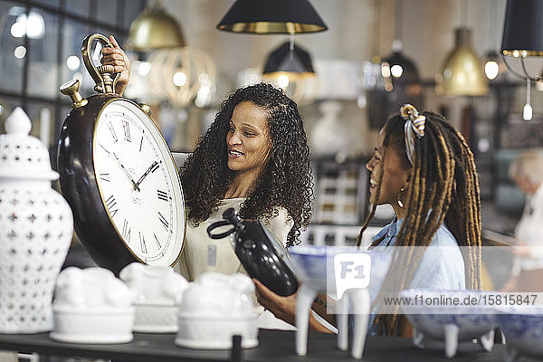 Women shopping for wall clocks in home decor shop
