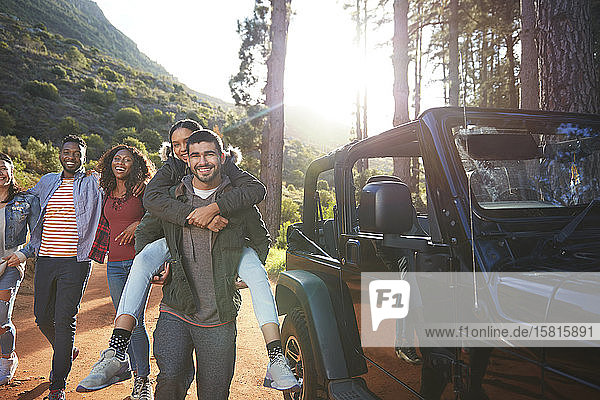 Portrait playful young friends enjoying road trip outside jeep