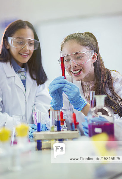 Lächelnde Studentin  die eine Flüssigkeit in einem Reagenzglas untersucht und ein wissenschaftliches Experiment in einem Laboratorium durchführt