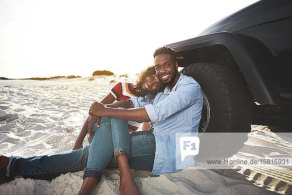 Porträt zärtliches junges Paar entspannt sich im Jeep am Strand