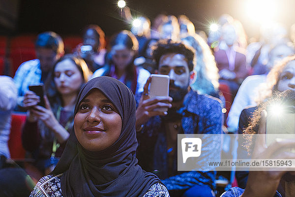 Lächelnde Frau im Hidschab hört im Publikum zu