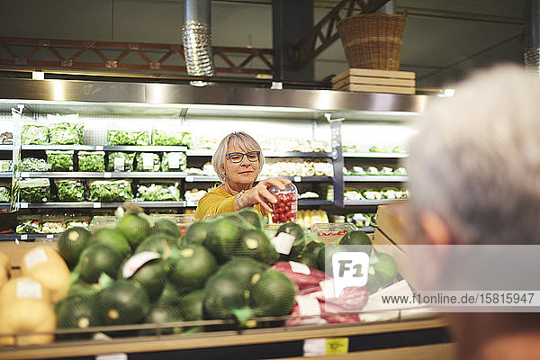Ältere Frau beim Einkaufen von Tomaten in der Gemüseabteilung eines Supermarkts