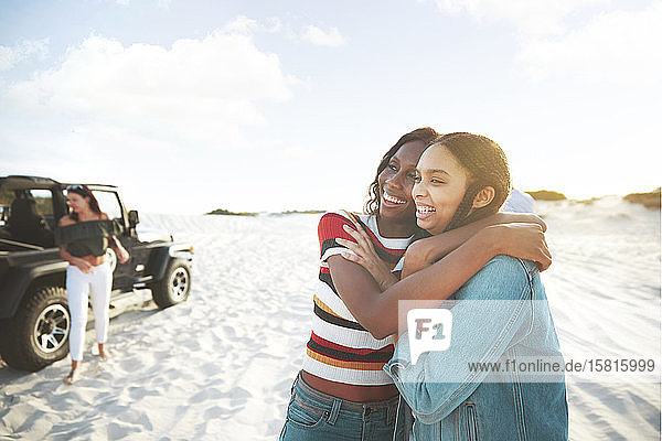 Happy young women friends hugging  enjoying beach road trip