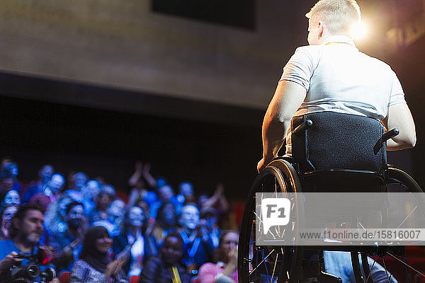 Das Publikum klatscht für eine Rednerin im Rollstuhl auf der Bühne