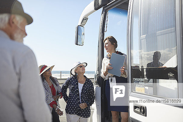 Reiseleiter im Gespräch mit aktiven älteren Touristen am Eingang des Reisebusses