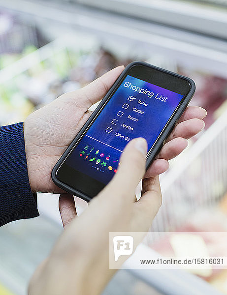 Nahaufnahme einer Frau  die eine digitale Einkaufsliste auf einem Smartphone im Supermarkt benutzt