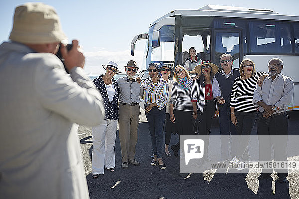 Aktive ältere Touristenfreunde posieren für ein Foto vor dem Reisebus