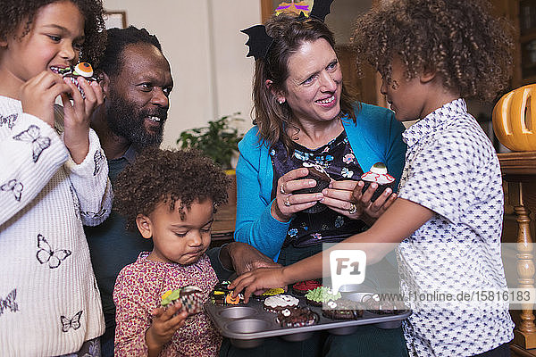 Multiethnische Familie isst dekorierte Halloween-Cupcakes