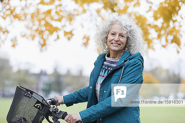 Porträt zuversichtlich  lächelnd ältere Frau Fahrradfahren im Herbst Park