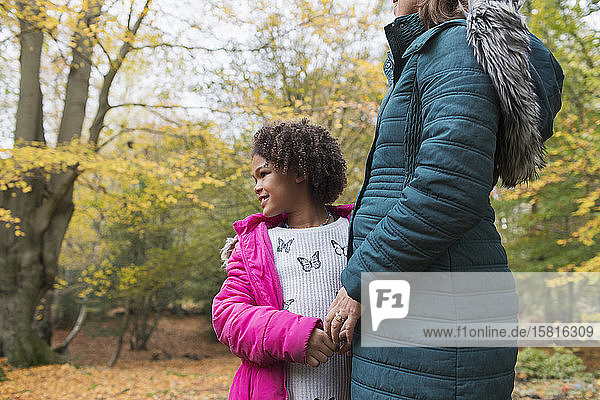 Glückliche Tochter hält Hände mit Mutter im Herbst Wald