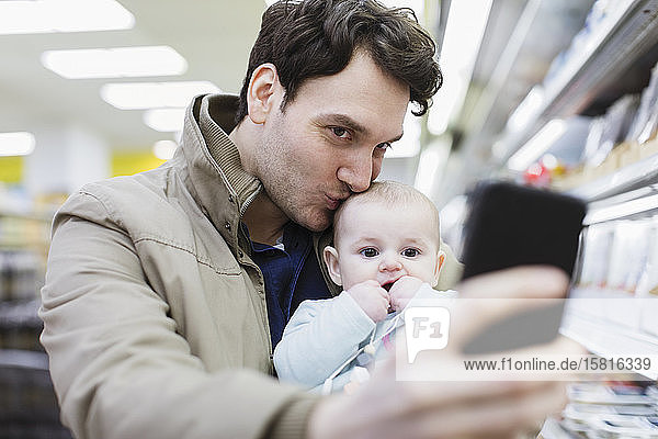 Zärtlicher Vater und kleine Tochter machen ein Selfie im Supermarkt