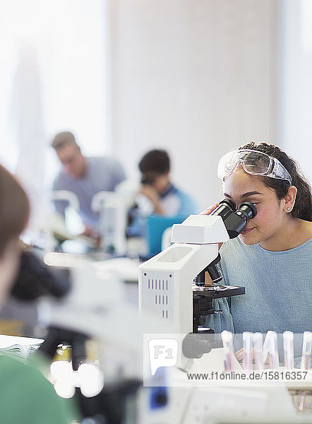 Girl student using microscope  conducting scientific experiment in laboratory classroom