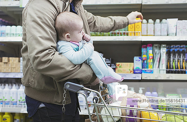 Vater mit Baby beim Einkaufen im Supermarkt