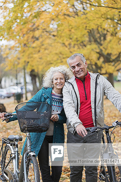 Portrait smiling  carefree senior couple with bicycles in autumn park