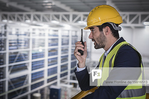 Male supervisor talking  using walkie-talkie on platform in factory