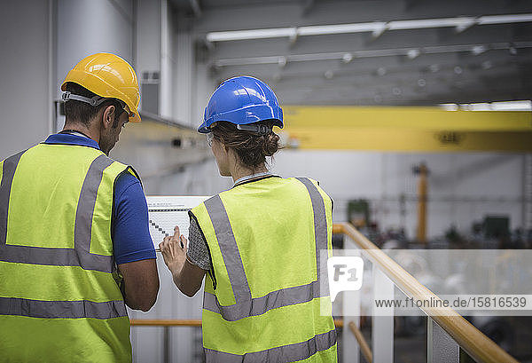 Aufsichtspersonen besprechen Papierkram auf einer Plattform in einer Fabrik