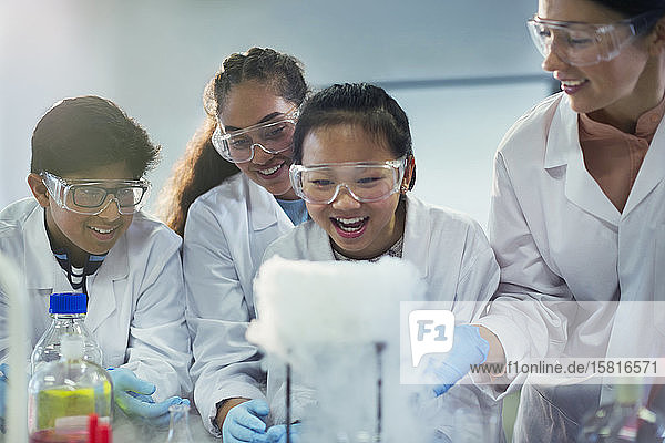 Neugierige  lächelnde Schüler  die eine chemische Reaktion beobachten und ein wissenschaftliches Experiment in einem Laboratorium durchführen