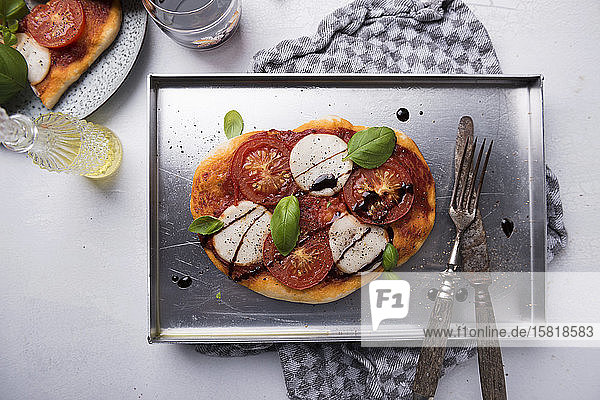 Pizza mit veganem Mozzarella  Tomaten  Basilikum und Balsamico-Essig