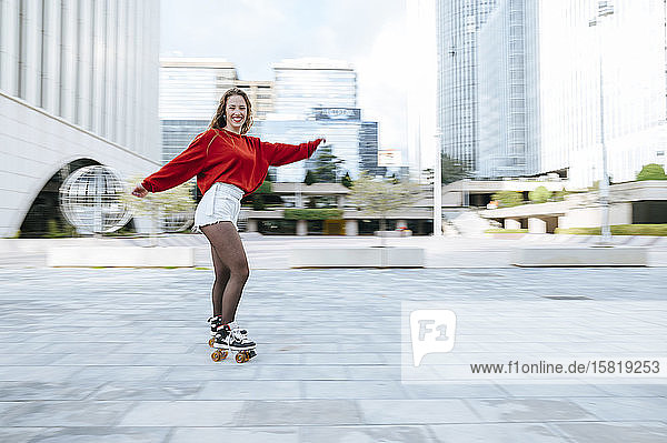 Portrait of happy young woman roller skating in the city