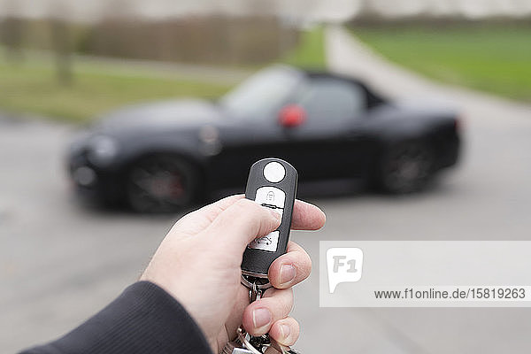Hand with key opening sports car