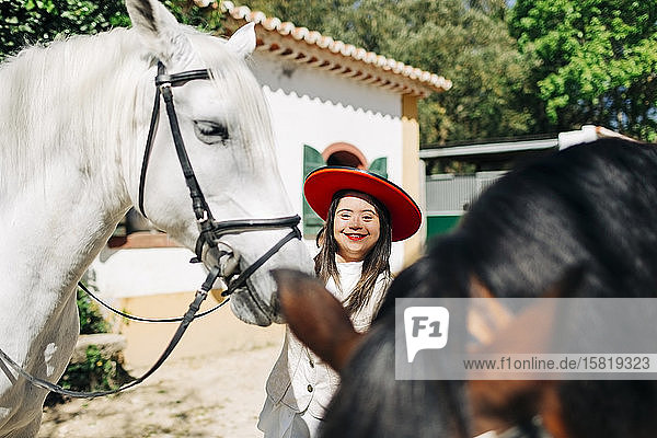 Teenager mit Down-Syndrom trägt roten Hut mit zwei Pferden