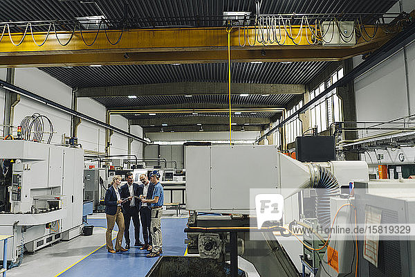 Business people and worker talking in a factory