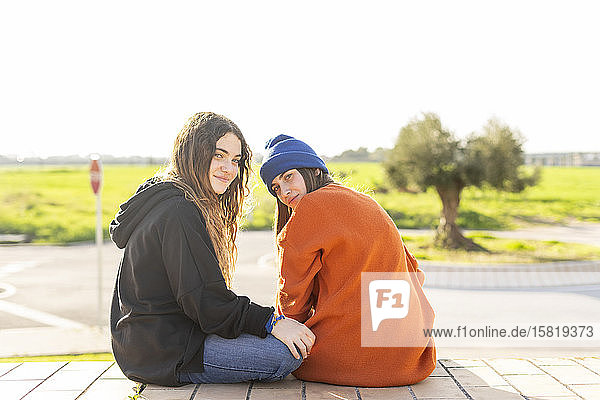 Porträt von zwei Mädchen im Teenager-Alter  die im Freien sitzen