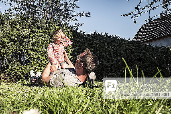 Vater spielt mit kleiner Tochter im Garten