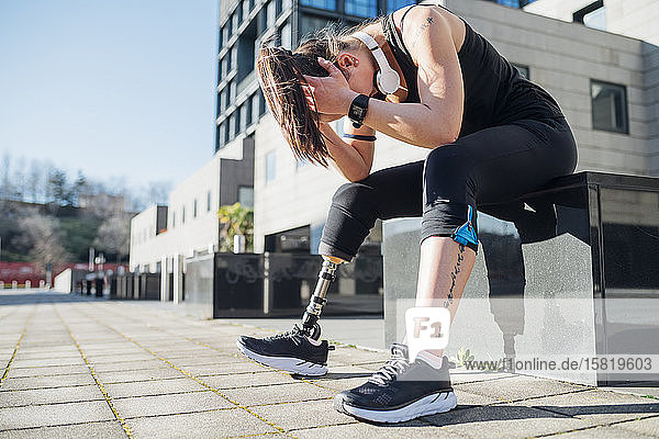 Exhausted sporty young woman with leg prosthesis in the city