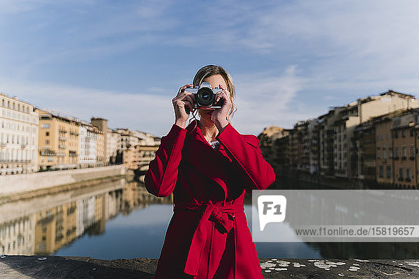 Young woman taking a picture on a bridge above river Arno  Florence  Italy