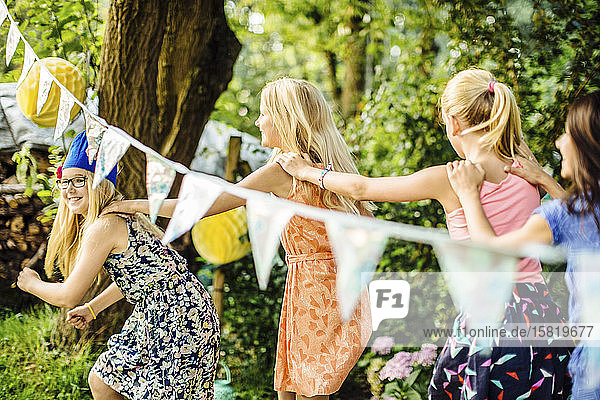 Glückliche Mädchen machen eine Conga-Linie auf einer Geburtstagsparty im Freien