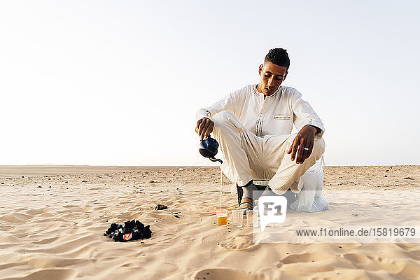 Mann gießt Tee in Gläser in der Wüste Sahara  Tindouf  Algerien