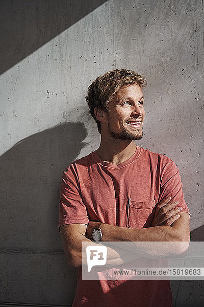 Porträt eines Mannes mit rotem T-Shirt an Betonwand