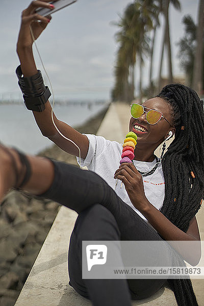Porträt einer lachenden Frau mit Dreadlocks  die sich mit einem Smartphone selbstständig macht  Maputo  Mosambik