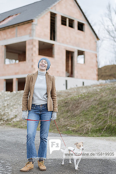 Porträt einer glücklichen  reifen Frau  die mit ihrem Hund Gassi geht